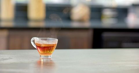 Elegant glass cup of warm tea on kitchen counter