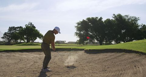 Focused Golfer Swinging in Sand Trap on Sunny Day - Download Free Stock Images Pikwizard.com
