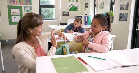 Teacher using sign language with young student in classroom