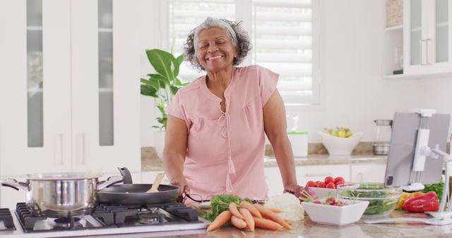 Portrait of happy senior african american woman cooking in kitchen. Retirement and spending time at home concept.