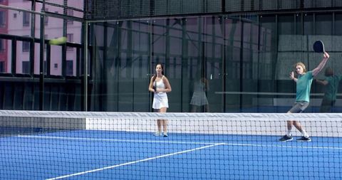Active Couple Playing Padel Tennis In Modern Glass Court