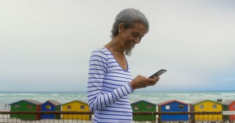 Active Senior Woman Taking Selfie by Beach with Colorful Huts - Download Free Stock Images Pikwizard.com