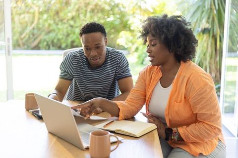 African american friends collaborating on laptop in bright home workspace