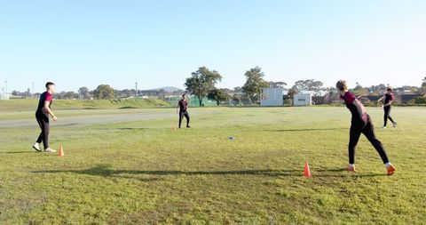 Athletes Practicing Throwing Techniques on Grass Field