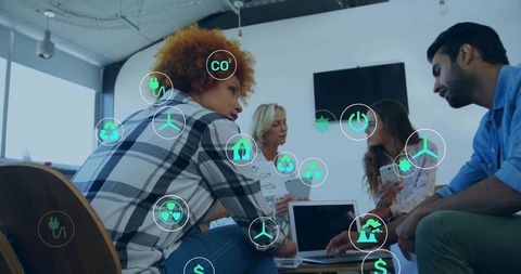 Diverse team brainstorming sustainable energy icons overlay in modern office meeting