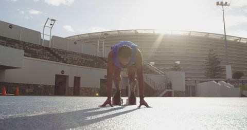 Male track runner preparing on starting blocks at stadium