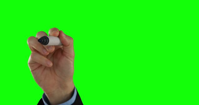 A Caucasian businessman's hand is holding a marker against a green screen background, with copy space. Ideal for presentations or advertising, the image allows for text or graphics to be superimposed next to the marker.