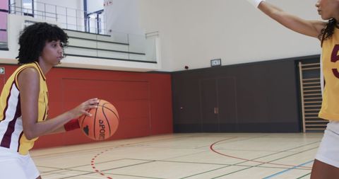 Female basketball players practicing intense dribbling skills indoors