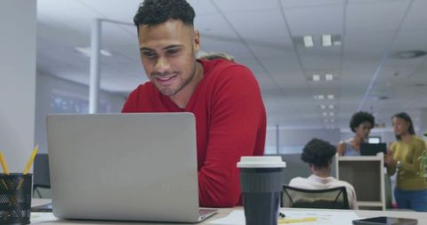 Man in Red Sweater Working on Laptop in Modern Office Environment