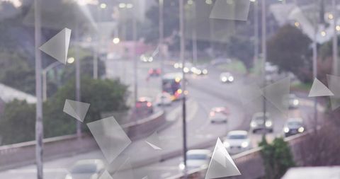 Curving urban highway at dusk with traveling cars, bokeh headlights and abstract triangle overlays