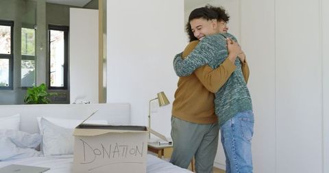 Father and son hugging near donation box in cozy bedroom