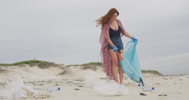 Woman wearing gloves cleaning up plastic waste on a beach. Concept of environmental conservation and pollution awareness. Ideal for topics on volunteering, environmental activities, and sustainability initiatives.