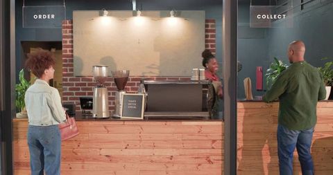Barista serving takeaway coffee to african american customers at rustic espresso counter