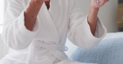 Senior Woman in White Bathrobe Applying Makeup at Home