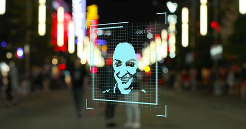 Digital facial recognition technology on city street at night