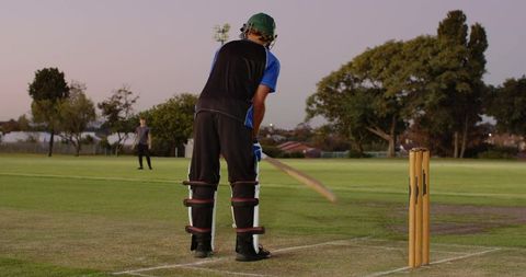 Batsman driving single while sprinting between creases during twilight local cricket match