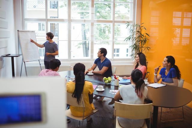 Group of colleagues engaging in a business meeting, with one person explaining points on a whiteboard. Ideal for illustrating teamwork, corporate training, professional development, and brainstorming sessions. Useful for corporate websites, business blogs, and employee training materials.