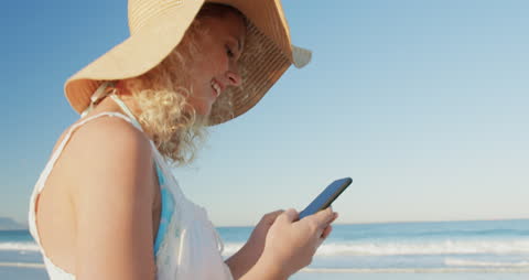 Smiling Woman Using Smartphone on Sunny Beach