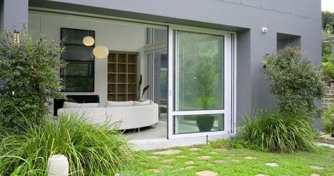Sliding glass door opening onto landscaped lawn with curved white sofa and stepping stones