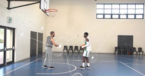 Coach guiding player during basketball drill on indoor blue court for team training
