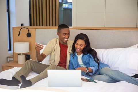 Joyful African American Couple Relaxing with Laptop on Bed