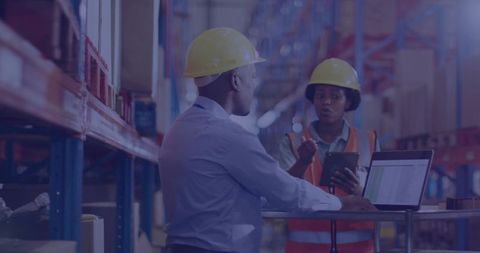 Warehouse supervisors inspecting inventory with tablet and laptop on mobile cart