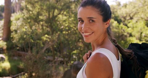 Smiling Woman with Backpack Enjoying Nature at Campsite