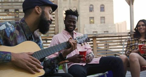 Friends enjoying rooftop party with live guitar music