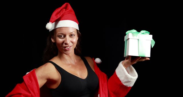 Joyful Woman Holding Christmas Gift in Santa Hat and Red Coat - Download Free Stock Images Pikwizard.com