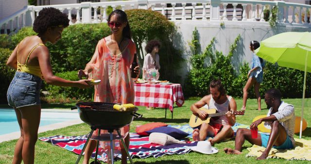 Group of friends enjoying summer barbecue by the poolside, perfect for content on outdoor activities, social events, and summer leisure. This energetic scene of grilling, relaxing on blankets, and playing guitar depicts the joy of communal summer celebrations.