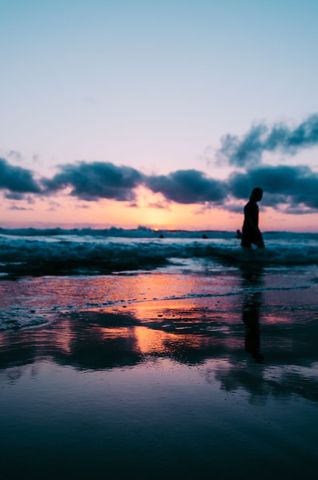 Silhouette Walking on Beach at Twilight