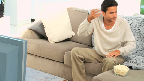 Man Relaxing with Popcorn While Watching TV at Home