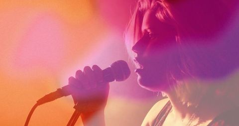 Teen singer performing with mic under colorful stage lights