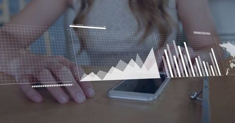 Young woman analyzing digital charts on smartphone at desk with holographic data graphs
