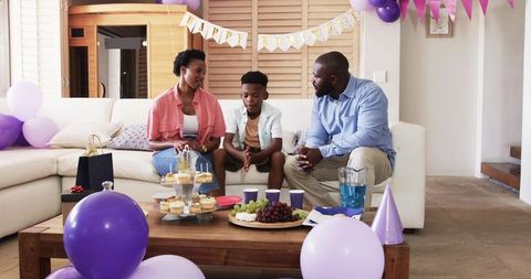 African American family celebrating birthday home with cupcakes balloons banner and gifts