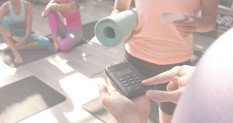 Outdoor yoga class accepting card payment with portable card reader and instructor
