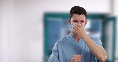Caucasian Healthcare Worker Adjusting Face Mask in Hospital Corridor