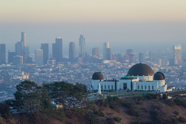 Scenic view of Griffith Observatory with the Los Angeles skyline in the backdrop during sunrise. Ideal for content related to travel, architecture, city landscapes, tourist attractions, and California landmarks.