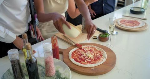 African american friends preparing homemade pizza on bright kitchen island with champagne