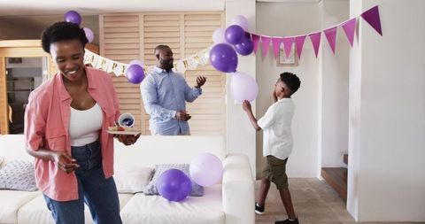 African American Family Celebrating Home Birthday with Purple Balloons, Cupcakes, Banner