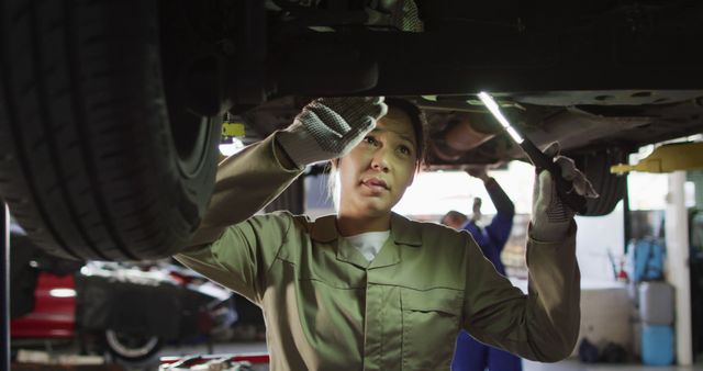 Image of biracial female car mechanic checking car. Working in car repair shop and running small feminine business concept.