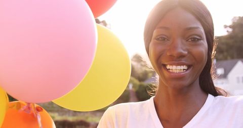 Smiling Woman Holding Colorful Balloons Outdoors on Sunny Day - Download Free Stock Images Pikwizard.com