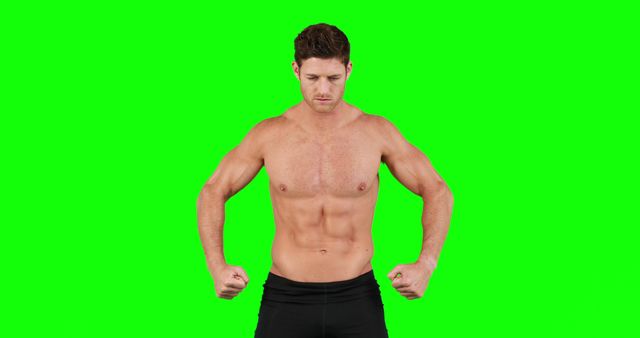 Fit, topless man showcasing his muscular body by flexing muscles against green screen. Useful for fitness ads, gym promotions, health and wellness campaigns, online workout videos, bodybuilding articles.