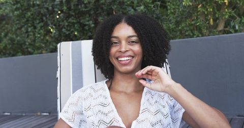 African american woman relaxing on striped deck chair wearing white crochet coverup