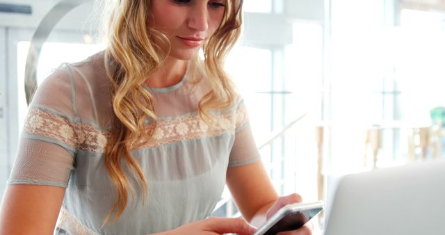 Young Woman Concentrating on Smartphone and Laptop in Modern Cafe - Download Free Stock Images Pikwizard.com