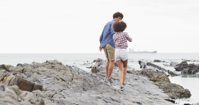 African american couple holding hands walking on the rocks near the sea - Download Free Stock Photos Pikwizard.com