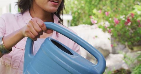 Woman Watering Garden with Blue Watering Can Outdoors