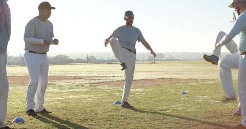 Baseball team warming up with high-knee drills on grassy infield at sunrise
