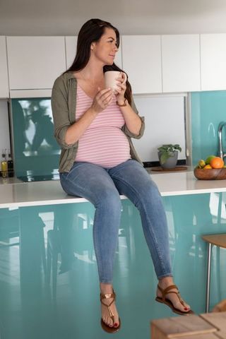 Pregnant Woman Relaxing with Mug on Modern Kitchen Island
