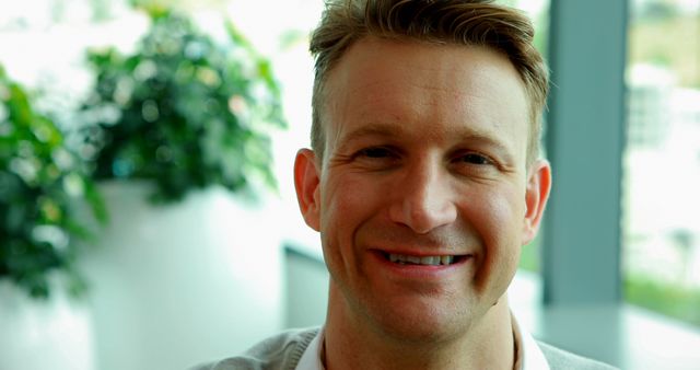 Middle-aged man smiling brightly in well-lit indoor environment. Could be used in business, lifestyle, or wellness content to convey positive mood, relaxation, and personal wellbeing. Effective for articles, advertisements, or blogs focusing on personal development, happiness, or work-life balance.